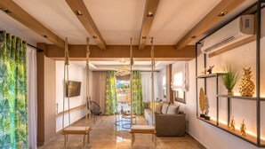 A modern interior with a wooden ceiling, a swing chair, a sofa, and a shelf with decorative items. - Ivoni Villa, Spacious Family Retreat • Pool & Play (Perama)