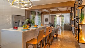 A modern kitchen with a central island, wooden chairs, and a hanging light fixture. - Ivoni Villa, Spacious Family Retreat • Pool & Play (Perama)