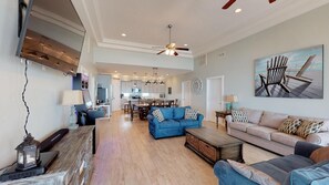 A spacious living area with a blue sofa, a wooden coffee table, and a ceiling fan.