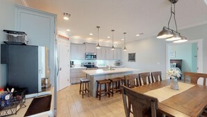 Una cocina moderna con una isla central, sillas de madera e iluminación colgante.