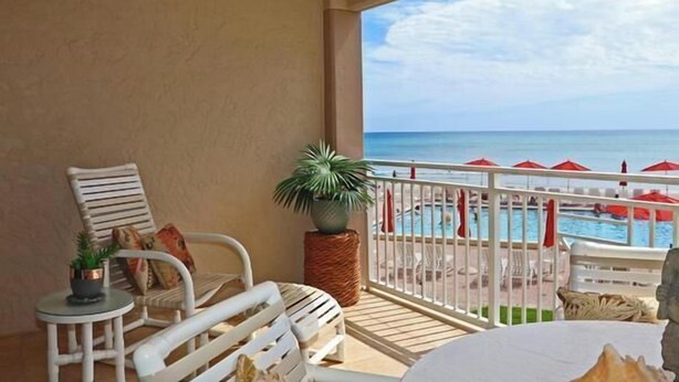 A balcony with white wicker furniture, a small table with a plant, and a view of a pool and beach. - Location, location, location.  Keep a close eye on the kids pool side, from this 2nd floor 2/2 condo (New Smyrna Beach)