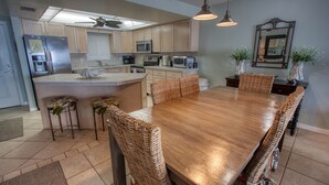 A modern kitchen with a central island, built-in appliances, and a dining area with wicker chairs. - Location, location, location.  Keep a close eye on the kids pool side, from this 2nd floor 2/2 condo (New Smyrna Beach)