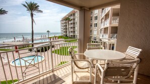 A balcony with a pool, chairs, and a view of the beach and ocean. - Location, location, location.  Keep a close eye on the kids pool side, from this 2nd floor 2/2 condo (New Smyrna Beach)