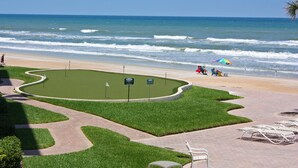 A beach with a paved walkway, green areas, and lounge chairs. - Location, location, location.  Keep a close eye on the kids pool side, from this 2nd floor 2/2 condo (New Smyrna Beach)