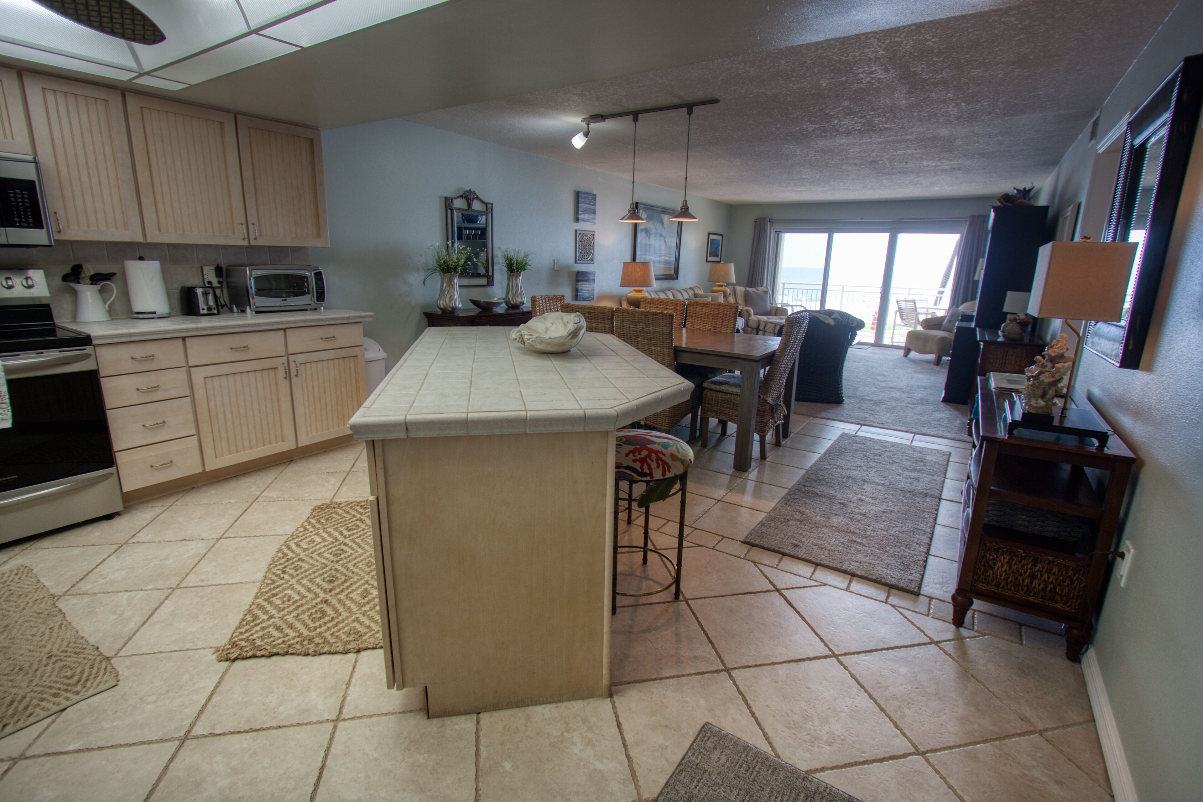 Una cocina amplia con una isla central, un comedor con mesa y sillas, y una sala de estar con sofá y televisor.