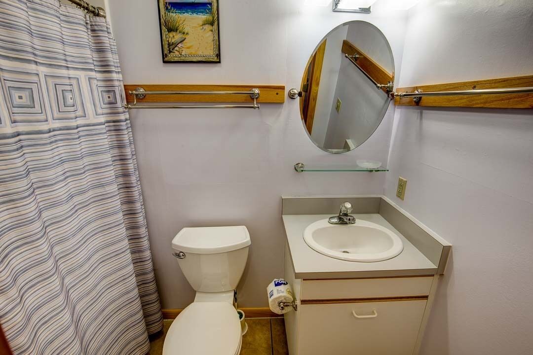 Un baño con inodoro, lavamanos, espejo y cortina de ducha.