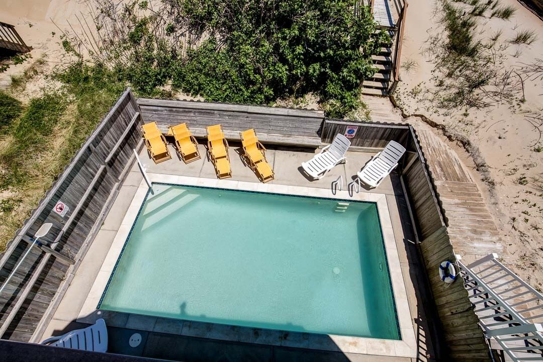 A rooftop pool with a clear view of the surrounding landscape, including sand dunes and vegetation.