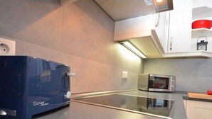 A modern kitchen with a built-in stove, microwave, and a blue appliance on the counter. - Vacation apartment Baltic Sea (ground floor) - barrier-free (Sellin)
