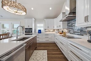 A modern kitchen with white cabinetry, a large island, and a patterned rug.