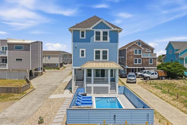 A two-story building with a balcony, a swimming pool, and a parking area.
