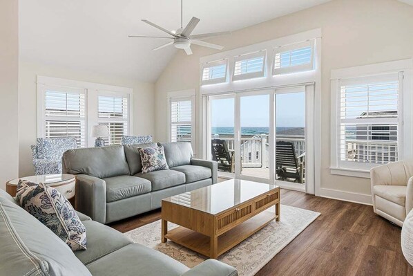 A spacious living room with a grey sofa, a wooden coffee table, and a ceiling fan.
