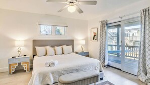 A bedroom with a large bed, two bedside tables, a ceiling fan, and a view of a balcony. - Summer Place | 325 ft from the beach | Private Pool, Hot Tub | Southern Shores (Southern Shores)