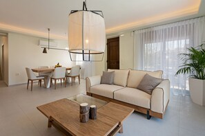 Ein modernes Wohnzimmer mit Sofa, Couchtisch, Esstisch, Stühlen und einer Pendelleuchte.