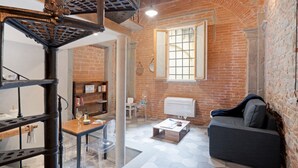 Une pièce de style loft avec des murs en briques apparentes, un escalier, un canapé, une table basse et une bibliothèque.