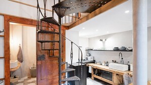 Une cuisine avec un escalier en bois, un évier et un four à micro-ondes.