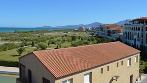 A building with a red-tiled roof, surrounded by greenery and a view of the sea and mountains. - 2-room apartment with mezzanine, pool, and parking in Saint Cyprien (Saint-Cyprien)