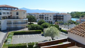 A residential area with multi-story buildings, a parking lot, and a view of mountains in the background. - 2-room apartment with mezzanine, pool, and parking in Saint Cyprien (Saint-Cyprien)