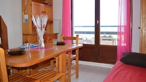A wooden dining table with chairs, a vase with flowers, and a view of the sea through a sliding glass door. - 2-room apartment with mezzanine, pool, and parking in Saint Cyprien (Saint-Cyprien)