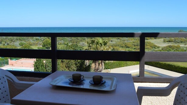 A balcony with a table set for two, overlooking a coastal landscape. - 2-room apartment with mezzanine, pool, and parking in Saint Cyprien (Saint-Cyprien)