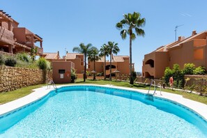 A swimming pool surrounded by buildings with a stone wall and palm trees. - Santa Maria, Marbella | Charming 2-Level Penthouse with Terraces, BBQ & Mediterranean Views in Marbella (Marbella)