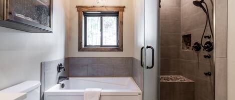 A modern bathroom with a bathtub, toilet, and shower area.