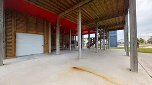 A covered outdoor area with a concrete floor, wooden pillars, and a red roof.