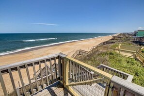 Una escalera de madera que lleva a una playa con vista despejada al océano.