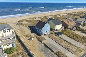 Une propriété située en bord de mer, comprenant plusieurs maisons, une plage de sable et une vue sur l’océan.