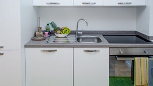 A modern kitchen with a stainless steel sink, a bowl of fruit, and a dish rack.