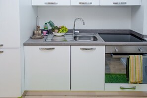 Une cuisine moderne avec un évier en acier inoxydable, un panier de fruits et un égouttoir à vaisselle.