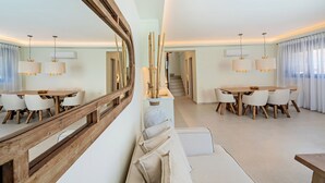 A modern dining area with two round tables, white chairs, and wooden accents. - 100m from the beach, hot tub, ping pong, sauna, gym & private sun beds! (Rethymno)