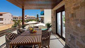 A terrace with a wooden table and wicker chairs, a glass-top table, and potted plants. - 100m from the beach, hot tub, ping pong, sauna, gym & private sun beds! (Rethymno)