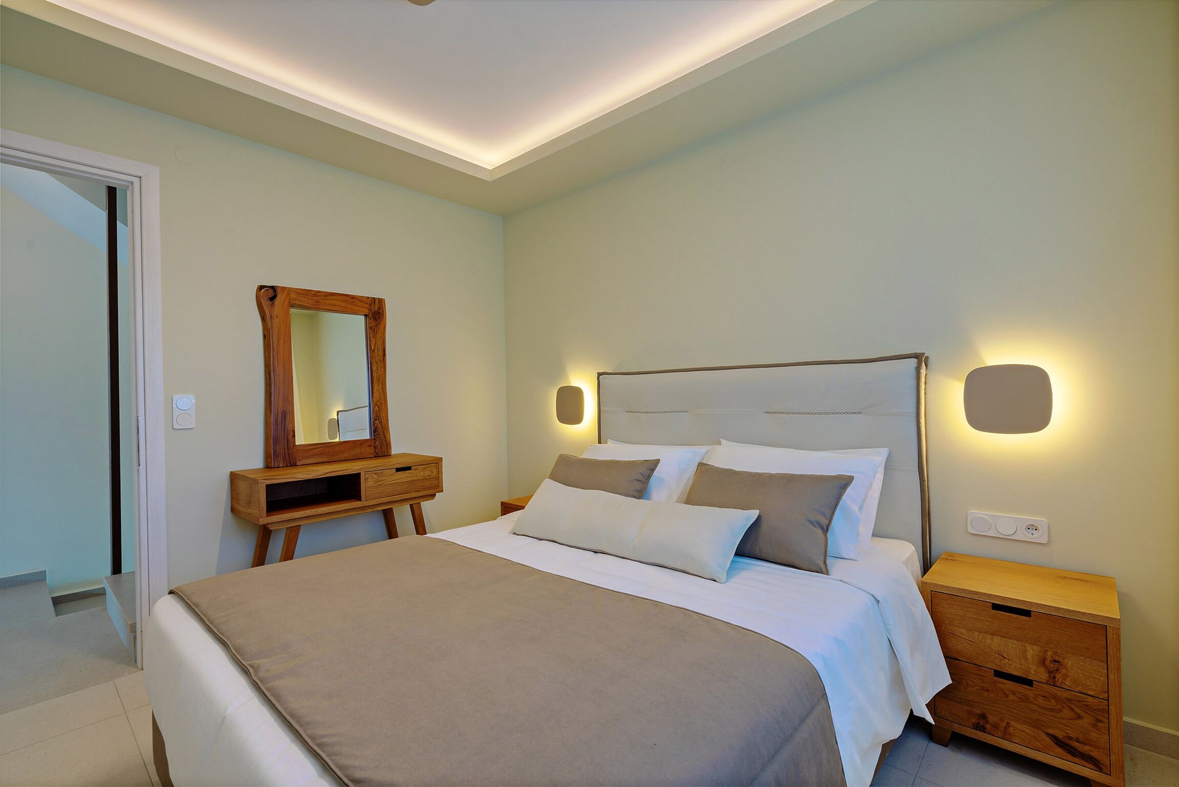 Une chambre à coucher comprenant un lit, une table de chevet, une commode et un miroir.