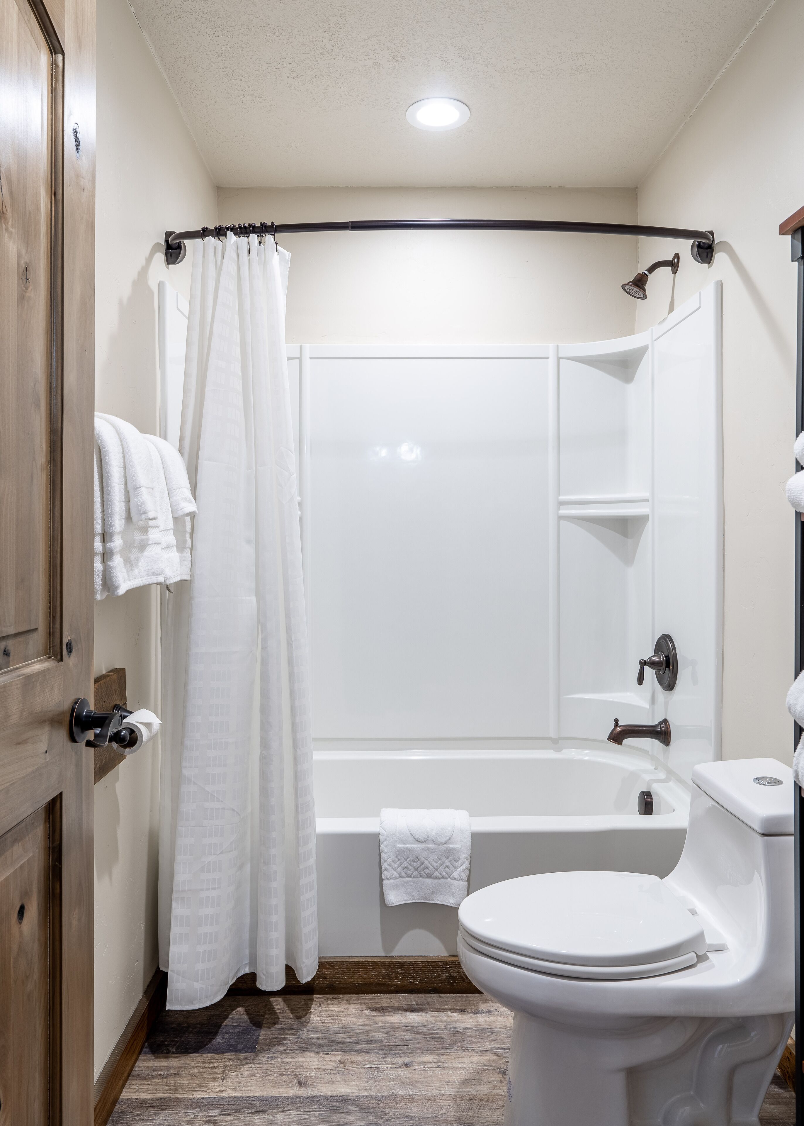 A bathroom with a bathtub, toilet, and a shower curtain.