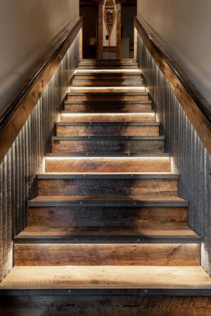 A wooden staircase with metal railings and a handrail. - The Adventure Inn Yellowstone (West Yellowstone)