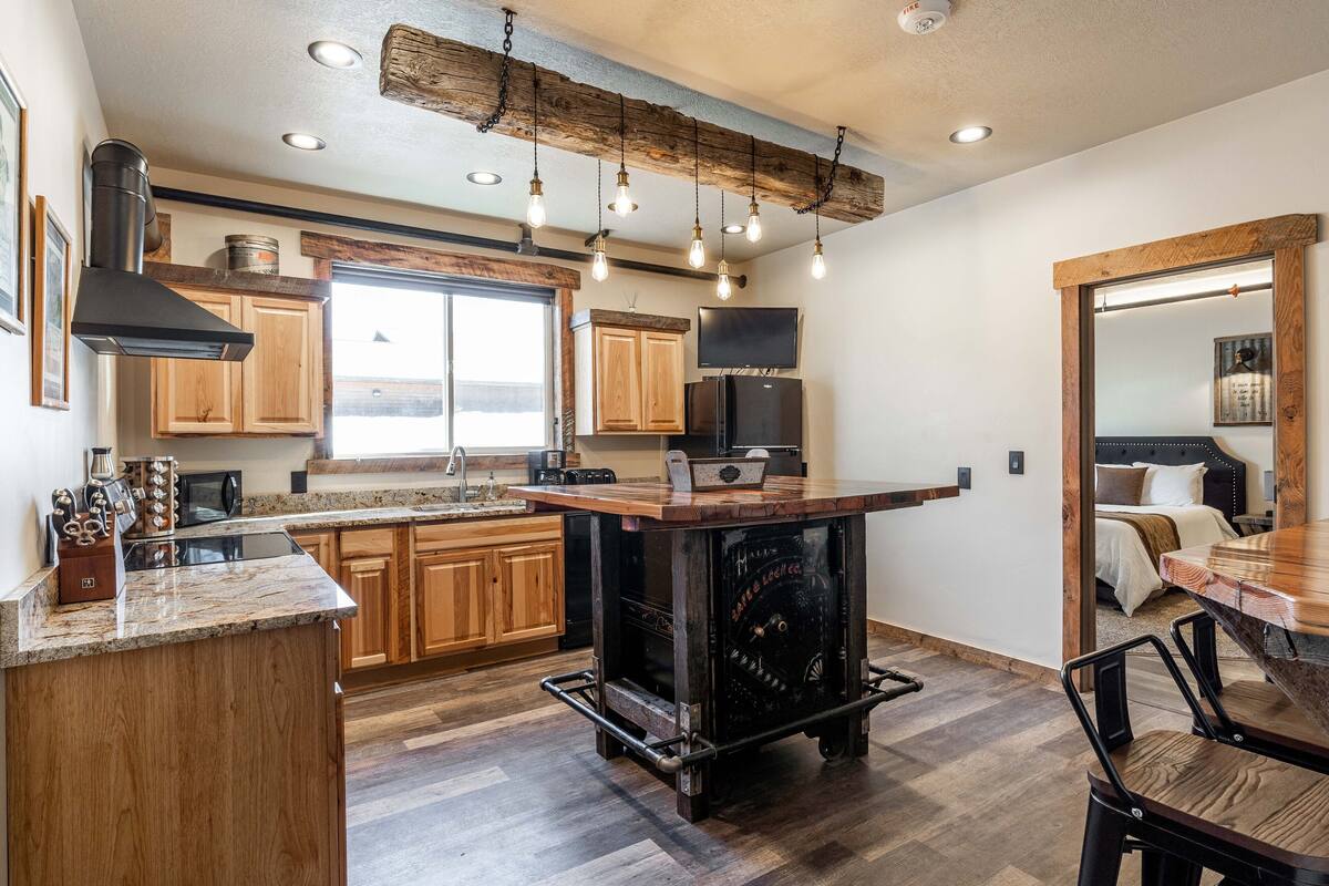 A modern kitchen with wooden cabinets, a central island, and a built-in stove.