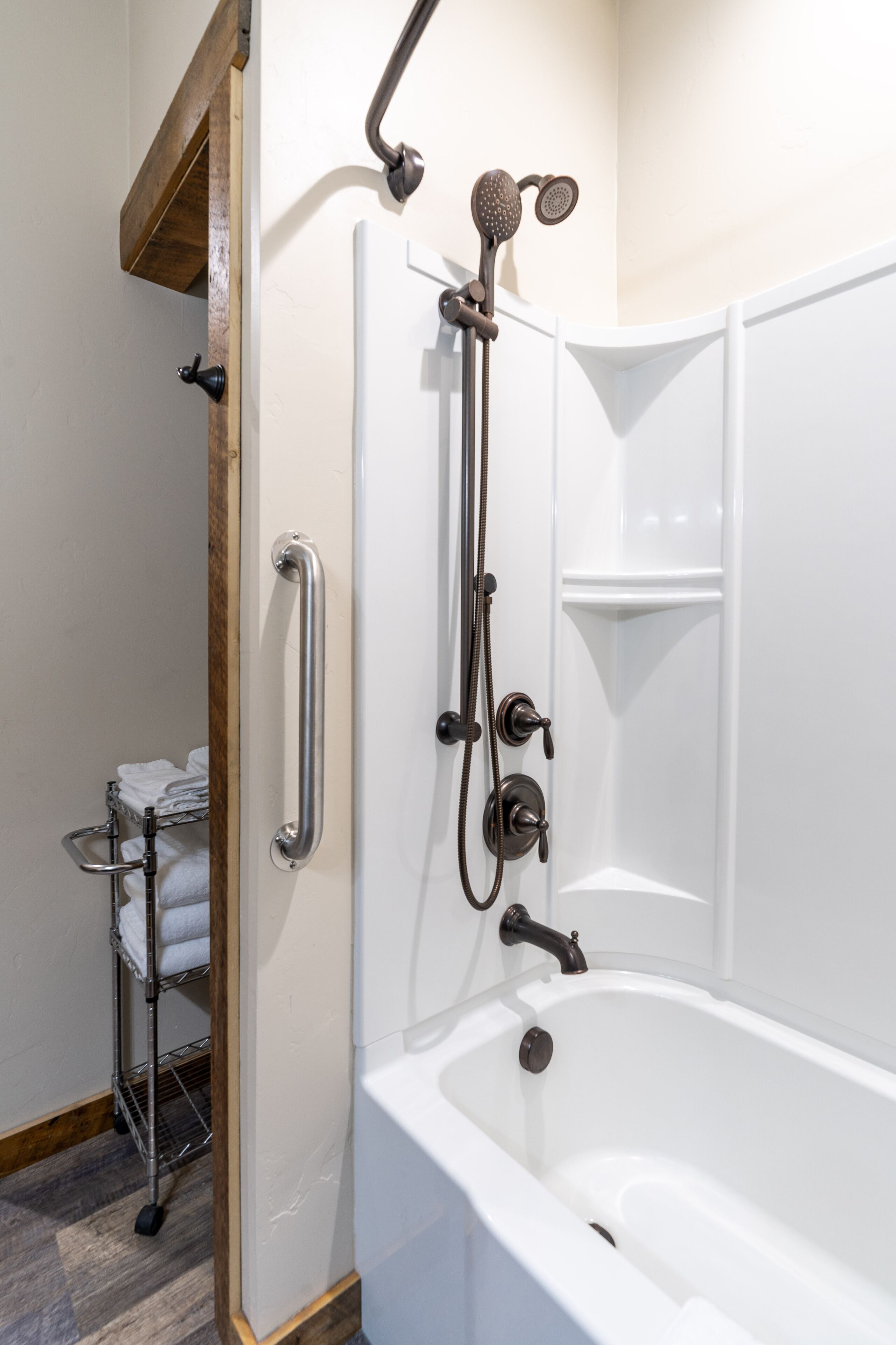 A modern bathroom with a walk-in shower, grab bars, and a white bathtub.