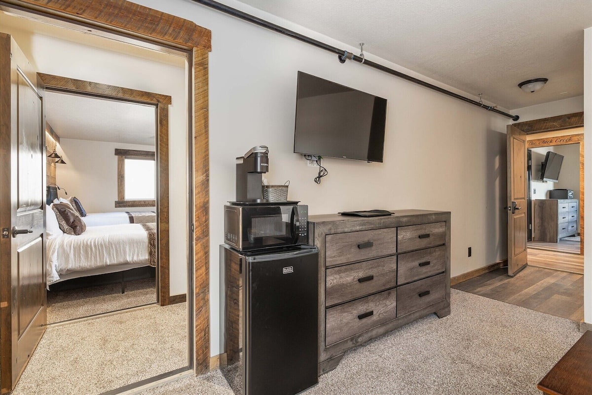 A hotel room with a bed, a coffee maker, a TV, and a dresser.