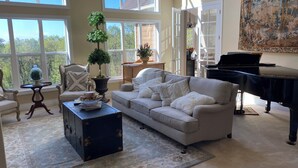 Uma sala de estar espaçosa com uma janela grande, um piano, um sofá e uma mesa de centro.