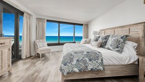 A bedroom with a large bed, a nightstand, a chair, and a view of the ocean. - Gulf View Balcony ~ Seasonally Heated Pool (Miramar Beach)