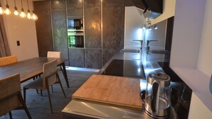 Una cocina moderna con comedor, horno empotrado y cafetera.