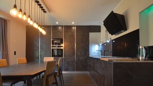 Una cocina moderna con encimera oscura, horno integrado y televisor de pantalla plana montado en la pared.