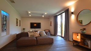 Una sala de estar moderna con un sofá marrón, un televisor de pantalla plana y un espejo grande.