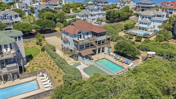 A residential area with houses, a swimming pool, and a view of the ocean. - Five Lucky Ducks | 400 ft from the beach | Dog Friendly, Private Pool, Hot Tub | Duck (Duck)
