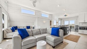 A modern living room with a sectional sofa, a dining area, and a kitchen. - Easy Livin' | 1040 ft from the beach | Private Pool, Hot Tub | Duck (Duck)
