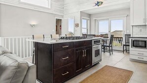 A modern kitchen with a central island, white cabinetry, and a view to the outside. - Easy Livin' | 1040 ft from the beach | Private Pool, Hot Tub | Duck (Duck)