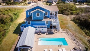 A large two-story house with a swimming pool and a covered patio area.