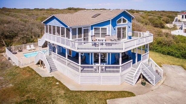 A two-story house with a balcony, a pool, and a deck.