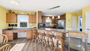 A kitchen with wooden cabinets, a central island with bar stools, and a refrigerator.