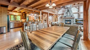 A spacious wooden interior with a large dining table, a stone fireplace, and a cozy seating area. - Stunning 5BR Family Lodge—Hot Tub, Huge Deck & Mountain Views (Silverthorne)